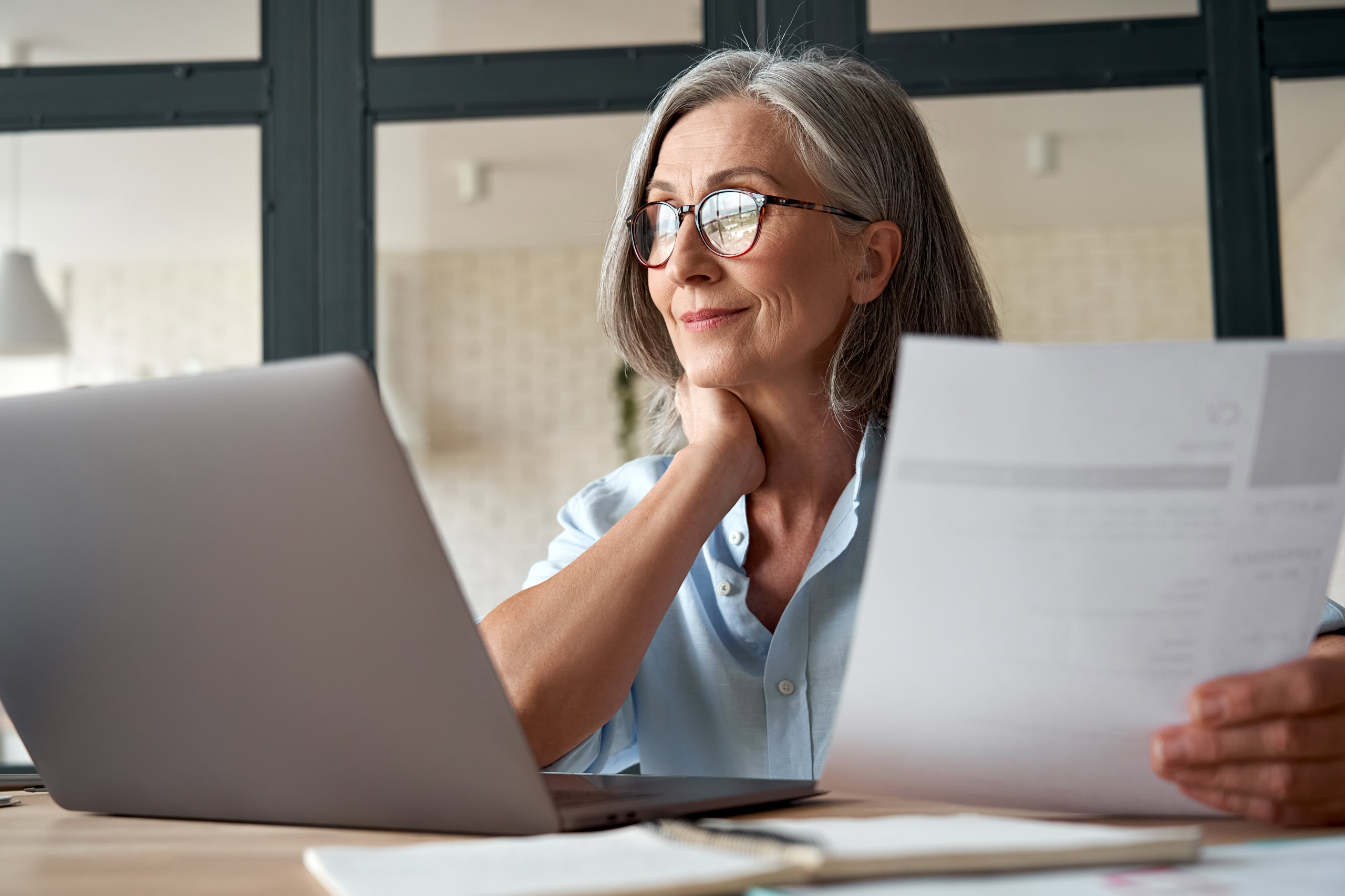 Frau mit Dokumenten am Laptop